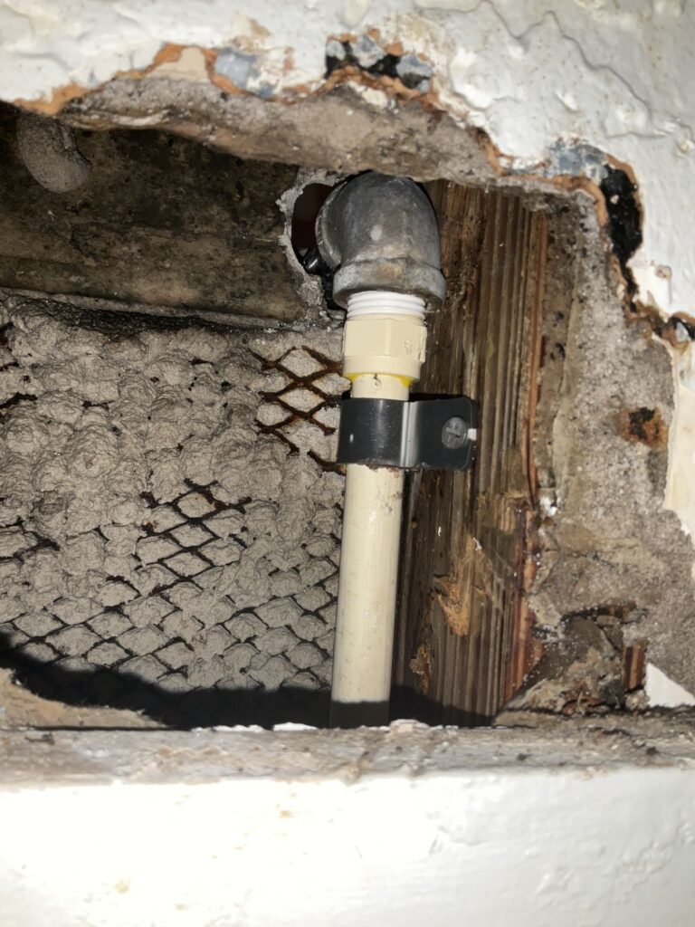 Galvanized elbow connected to a strapped CPVC riser inside an opened wall
