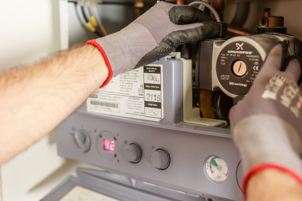 Plumber servicing a water heater and checking the pressure gauge