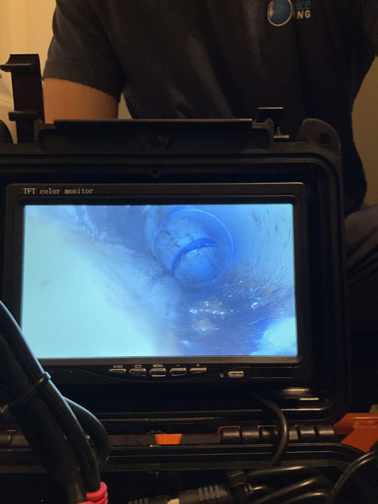 Sewer camera monitor showing a joint in the pipe while a technician holds the case
