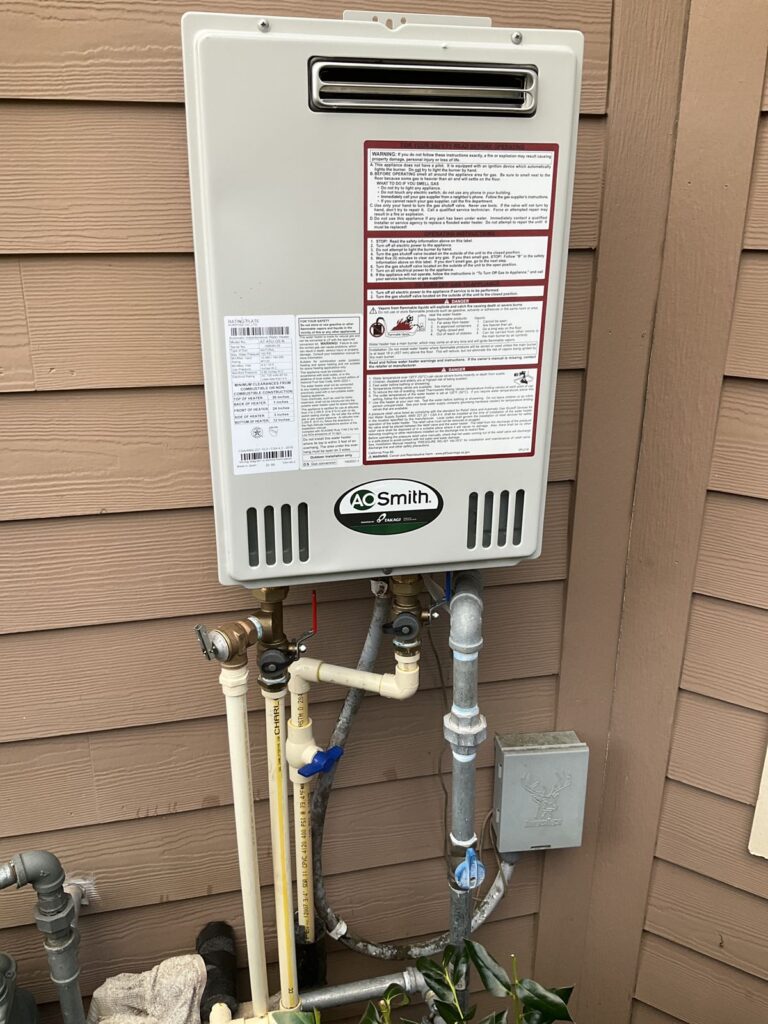 Exterior tankless water heater with gas piping, isolation valves and water lines below the unit