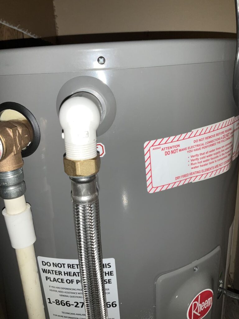 Braided flex water connector and brass union at the top of an electric water heater