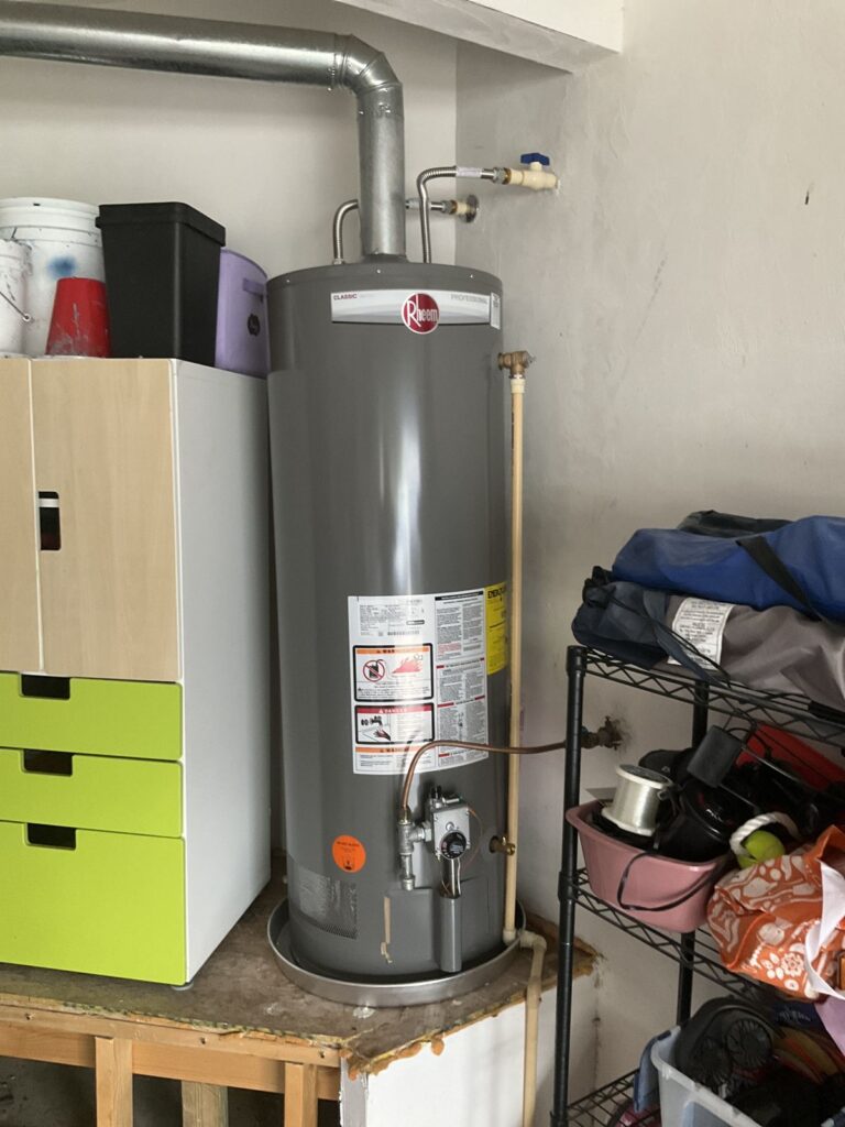 New gas water heater installed on a garage platform with the flue and gas line connected