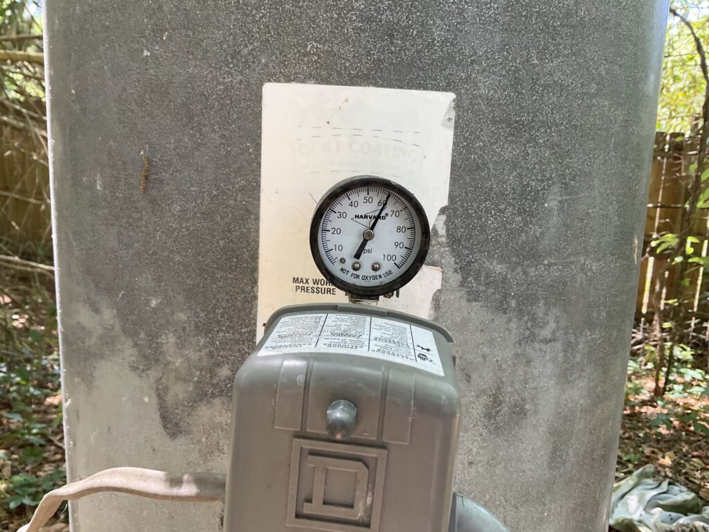 Close view of the pressure gauge and pressure switch on a galvanized well tank