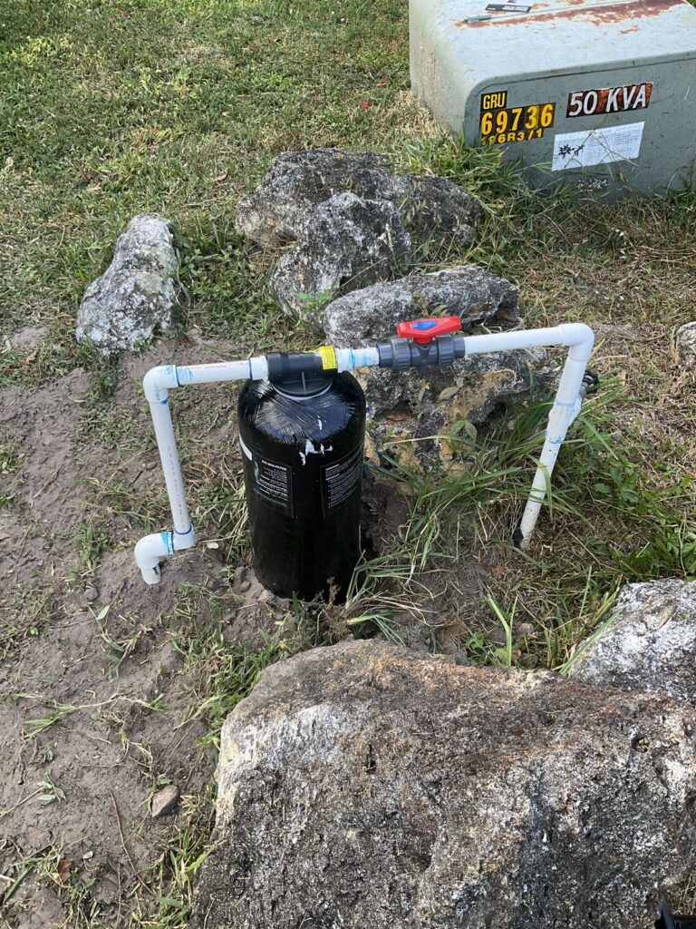 Installed whole house water filter and PVC manifold with a shutoff valve by a utility transformer